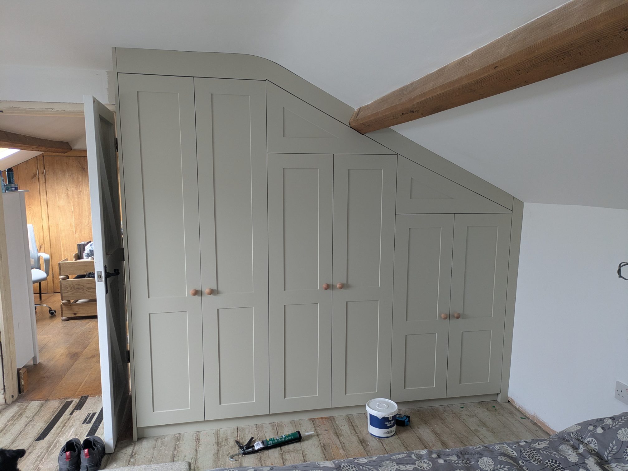Painted Shaker-style fitted wardrobes built to follow a sloping loft ceiling